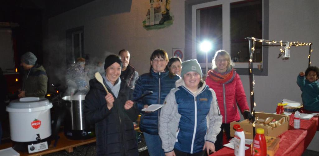 Mitglieder der Bäurinnen hinter dem Essensstand beim Würstel austeilen