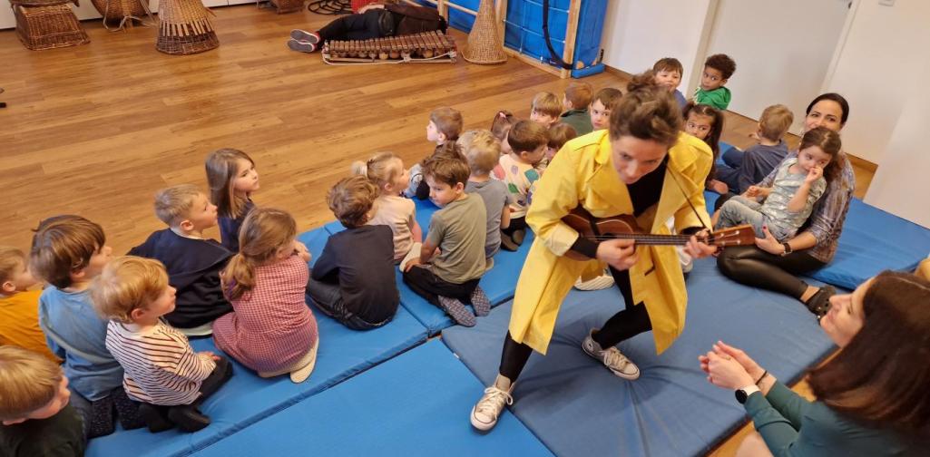 Verena Eder Die Künstlerin inmitten der Kinder beim Gitarre spielen