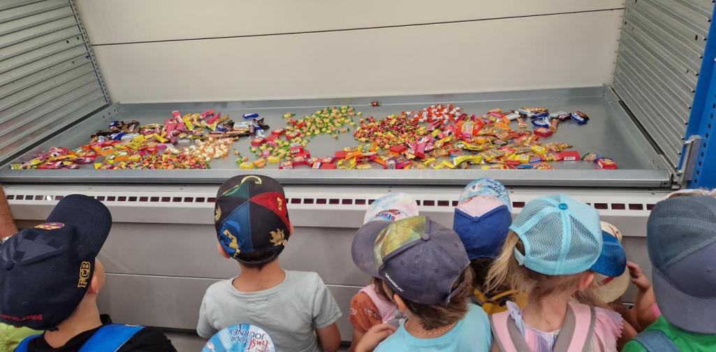 Verena Eder Die Kinder schauen in die Hochlagerlade, die mit Süßigkeiten gefüllt ist