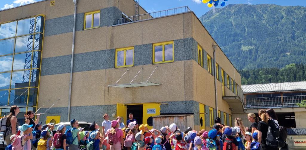 Verena Eder Die Kinder vor der Firma SFS, alle schauen den steigenden Luftballonen nach