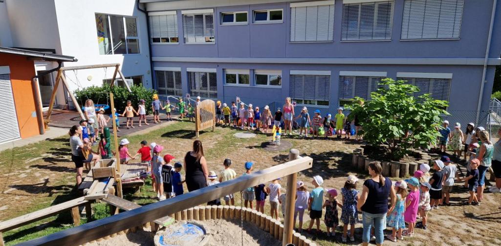 Verena Eder Alle Kinder vom Kindergarten bilden einen Kreis im Garten und singen Lieder