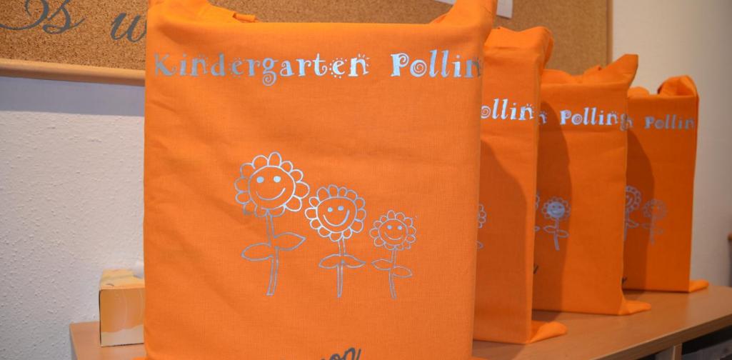 Vier orange Stoffsäcke mit den Kg Blumendesign und den Namen des Vorschulkindes