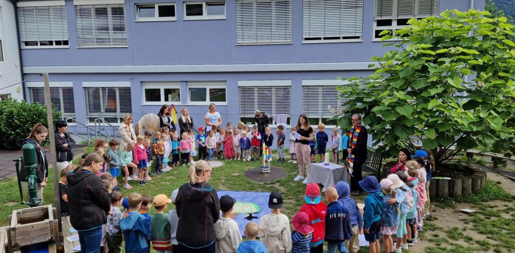 Verena Eder Alle Kinder und die Betreuer und der Pfarrer stehen im Kreis im Garten des Kindergarten