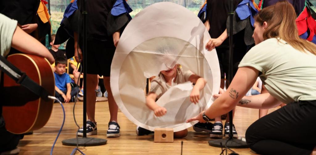 Ein mit Pergamentpapier bespannter Holzreifen in Form eines Ei, durch das ein Kind mit der Faust schlägt