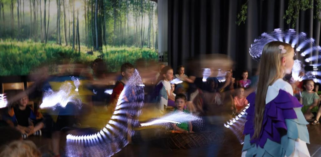 Kinder auf der Bühne die mit einem leuchtenden Stab die Sterne darstellen