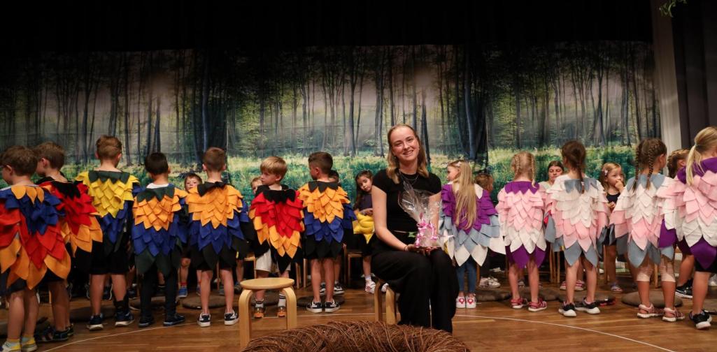 Letizia Gritscher, eine Schülerin der Modeferrari, sitzt auf der Bühne zwischen den Kindern die ihre genähten Kostüme präsentieren