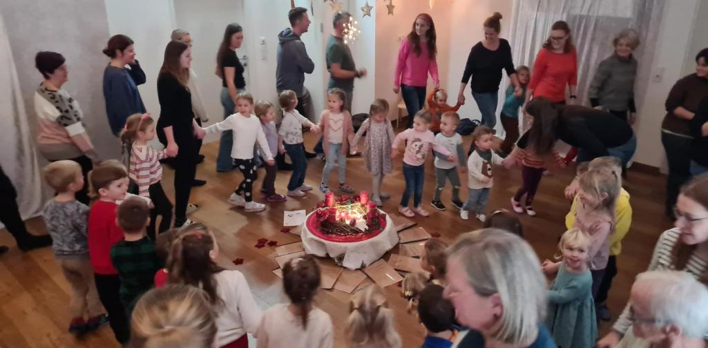 Verena Eder Die Kinder und die Erwachsenen tanzen rund um den Adventkranz