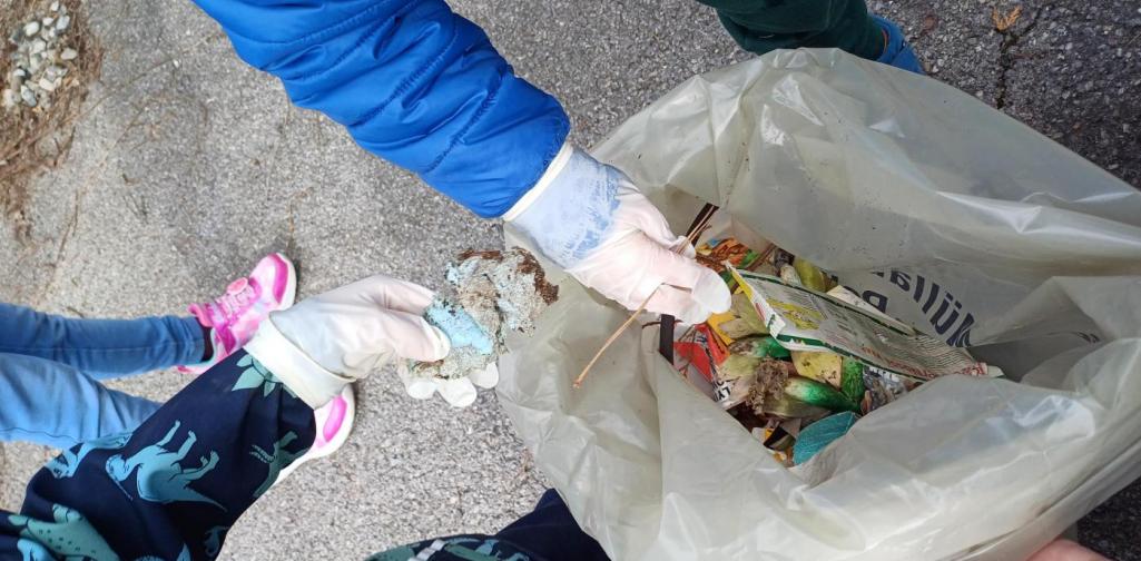 Verena Eder Kinderhände, die Handschuhe anhaben, werfen Müll in den Sack