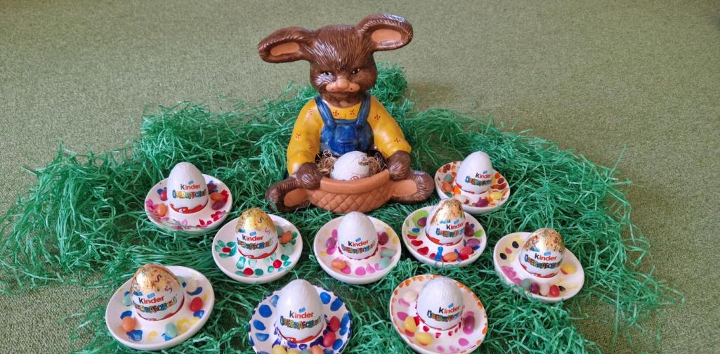 Verena Eder Die von den Kindern verzierten Eierbecher liegen auf Ostergras. Zur Dekoration sitzt ein Keramikhase inmitten des Nestes. In dem Eierbecher ist ein Überraschungsei und Drageeeier