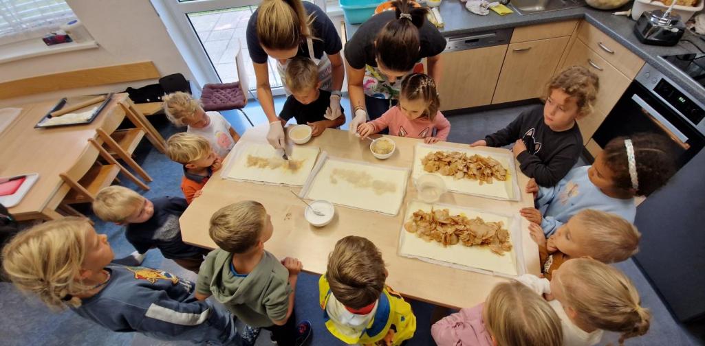 Verena Eder Die Kinder stehen rund um den Tisch und helfen beim Apfelstrudel backen