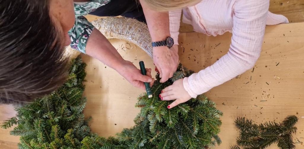 Verena Eder Ein Kind hilft Birgit beim Kranz binden