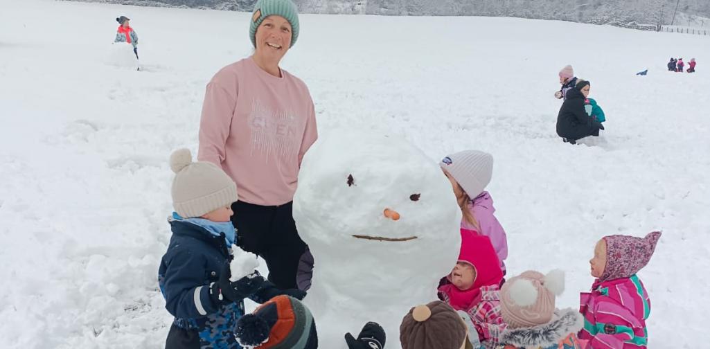 Verena Eder Die Kinder und die Pädagogin stehen um den großen Schneemann