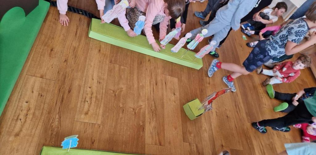 Kinder stecken Papiermenschen in einen dafür vorgesehenen Block, der neben dem Weg steht. Sie spielen die Geschichte vom Einzug (Palmsonntag) nach