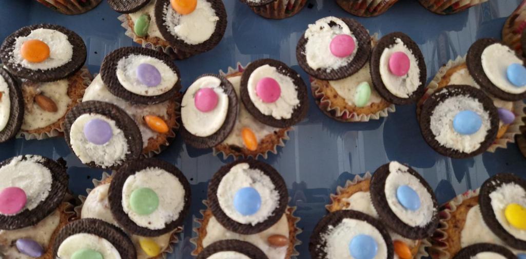 Viele Muffins die  als Eulen verziert worden sind. Geöffnete Oreos mit Smarties sind die Augen und ein Smartie die Nase