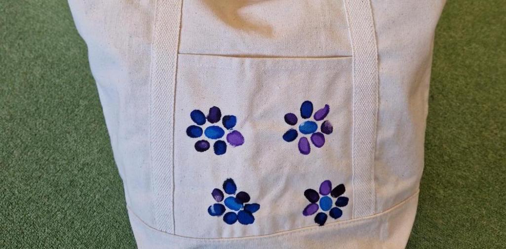 Eine Stofftasche mit Fingerabdrücken der Kinder in Form von blau-lila Blumen