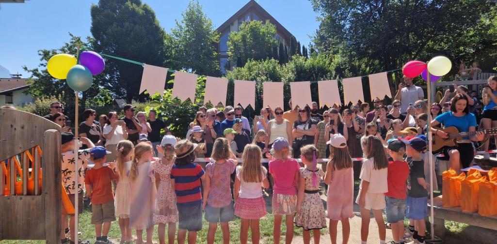 Die Schulkinder stehen verkehrt unter dem Schulkind-Banner. Zu sehen sind alle Besucher
